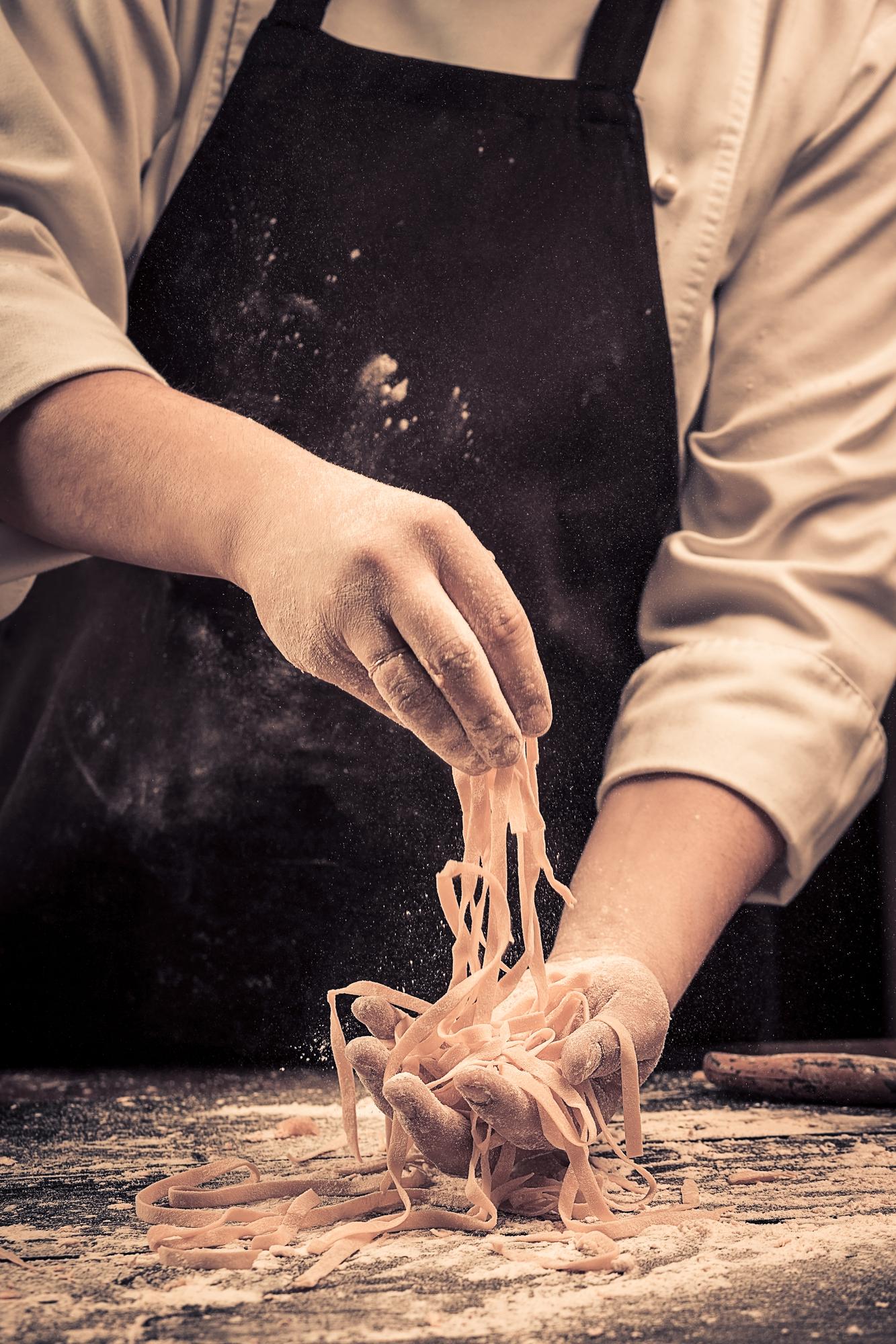 Chef che impasta pasta fresca in cucina artigianale